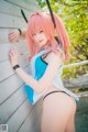 A woman with pink hair leaning against a wooden wall.
