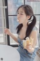 a woman sitting at a table eating a banana