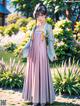 A woman in a pink and blue dress standing in a garden.