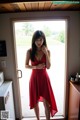 A woman in a red dress standing in front of a door.