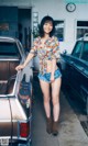 A woman standing next to a car in a garage.