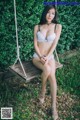 A woman sitting on a swing in a white bra and panties.