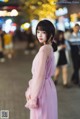 A woman in a pink dress standing in the middle of a street.