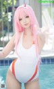 A woman in a white and orange bathing suit posing by a pool.