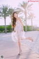 A woman in a white dress is walking on a boardwalk.