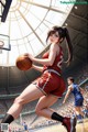 A woman in a red uniform holding a basketball on a court.