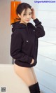 A woman in a black hoodie is posing for a picture.