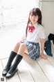 A young woman in a school uniform sitting on the floor.