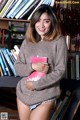 A woman standing in front of a bookshelf holding a book.