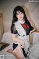 A woman in a maid outfit sitting on a bed.