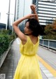 A woman in a yellow dress standing on a sidewalk.